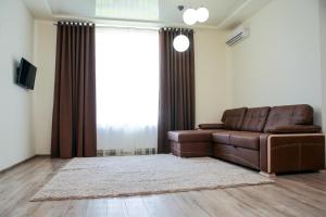 ein Wohnzimmer mit einem braunen Ledersofa und einem Fenster in der Unterkunft Family House in Winnyzja