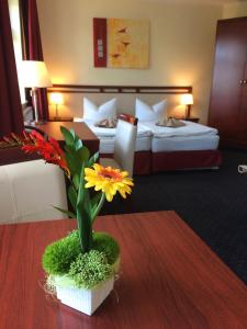 una habitación de hotel con una mesa con un jarrón de flores en SchlafGut AppartementHotel, en Leipzig