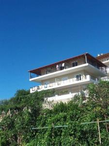 a white building on top of a hill with trees at Apartments Aneta's House in Himare