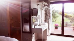 a bedroom with a desk with a television and a window at Golden Hill Guest House in Omagh