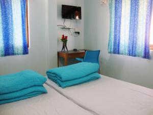 Habitación con cama con almohadas azules y mesa. en The Port Vista en Port Blair
