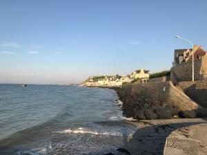 a beach with houses and the ocean on a sunny day at Vue mer à Arromanches in Arromanches-les-Bains