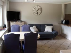 a living room with a couch and a table and a clock at Apartment in Kirchhundem in the middle of nature in Silberg