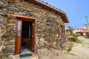 een stenen huis met een deur en een stenen muur bij Casa do Conto in Doade