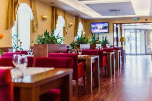 restauracja z czerwonymi krzesłami i stołami oraz telewizorem w obiekcie Grein Hotel w mieście Rzeszów