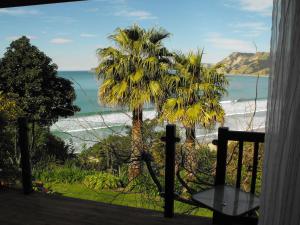 a view of the ocean and palm trees from a balcony at Rangimarie Anaura Bay Beachstay in Anaura Bay