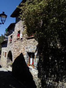 Casa del Arco في Aísa: مبنى حجري مع ظل شجرة