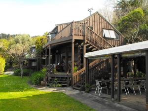 a house with a deck with tables and chairs at Rangimarie Anaura Bay Beachstay in Anaura Bay