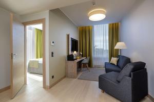 a living room with a couch and a chair and a bedroom at Centennial Nexus Hotel Tallinn in Tallinn