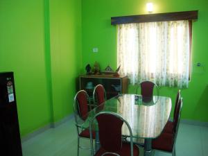 comedor con paredes verdes, mesa y sillas en The Port Vista en Port Blair