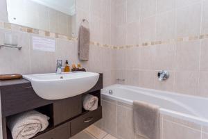 a bathroom with a white sink and a bath tub at Blue Horizon Guest House in Gordonʼs Bay