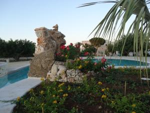 a garden in front of a pool with flowers at Masseria Valente in Ostuni