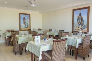 un comedor con mesas, sillas y una pintura en Blue Horizon Guest House, en Gordonʼs Bay