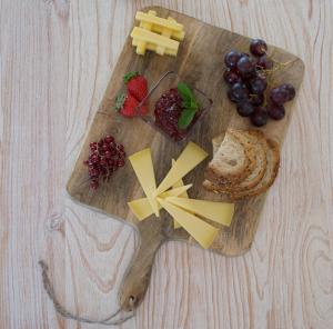 a wooden cutting board with cheese and fruit on it at Agroturismo Son Vives Menorca - Adults Only in Ferreries