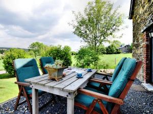 uma mesa de madeira e cadeiras num pátio em Romantic holiday house in the Ardennes with garden and view em Nadrin