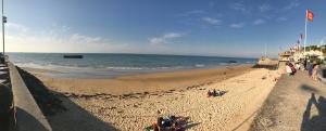 a beach with people on the sand and the ocean at Vue mer à Arromanches in Arromanches-les-Bains