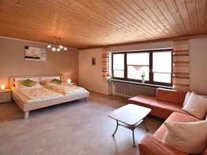 een grote kamer met een bed en een bank bij Charming holiday flat in the Bavarian Forest in Gleißenberg