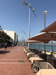 ラスパルマス・デ・グランカナリアにあるEstudio Paseo Las Canterasのビーチのパラソル付きテーブルと椅子