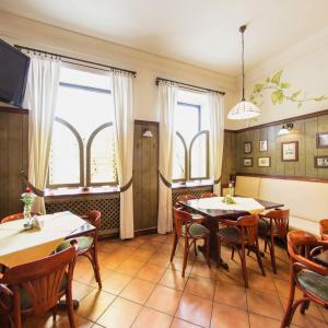 a dining room with two tables and chairs and windows at Apartamenty Kajzer in Kraków