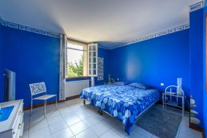 a blue bedroom with a bed and a window at Gîte Le Planier in Saint-Priest