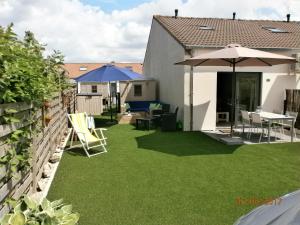 a backyard with green grass and umbrellas at Vakantiehuisje Bredene in Bredene