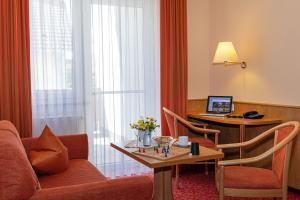 une chambre d'hôtel avec un canapé et un bureau avec un ordinateur dans l'établissement Gasthof - Hotel zum Ochsen GmbH, à Blaubeuren