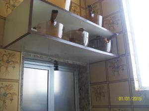 una cocina con ollas y sartenes en estanterías sobre una puerta en Apartamento Edificio Mirage, en Salvador
