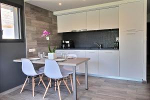 a kitchen with a wooden table and white cabinets at Residence ACQUA LINDA Porticcio in Porticcio