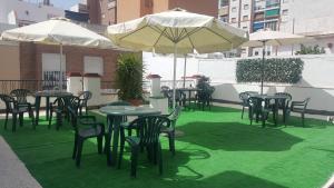 een groep tafels en stoelen met parasols bij Pension Yna Holiday in Málaga