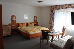 a bedroom with a bed and a table and a chair at Landgasthof Hotel Sauer in Willingen