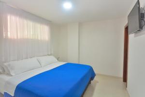 Cama azul en habitación blanca con ventana en Hotel Getsemaní BGA en Bucaramanga