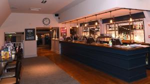 a bar in a pub with a counter and a clock at Olde House, Chesterfield by Marston's Inns in Chesterfield