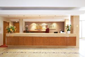 un homme debout derrière un comptoir de réception dans le hall dans l'établissement Universal Hotel Romantica, à Colonia Sant Jordi