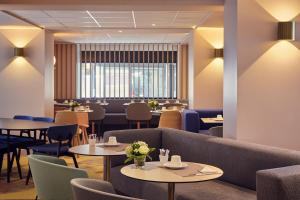 a restaurant with tables and chairs and a couch at Mercure Rouen Centre Cathédrale in Rouen