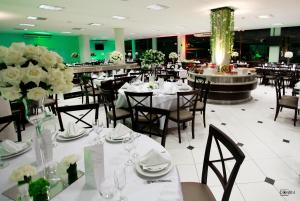 a restaurant with white tables and chairs and flowers at Hotel e Restaurante Bordignon in Joaçaba