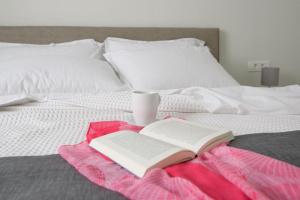 ペリッサにあるDe_naxia Suitesのベッドの上に置かれた本とカップ