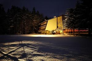 un gran edificio en la nieve por la noche en Zajazd u Kmity, en Postołów