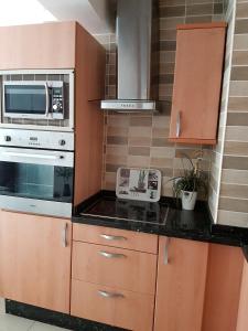 a kitchen with wooden cabinets and a microwave and a stove at Apartamento en el centro de Nerja in Nerja