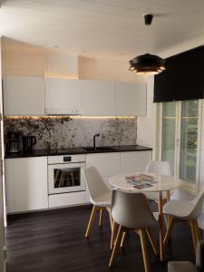 a kitchen with white cabinets and a table and chairs at Apartment Suutarintie in Rovaniemi