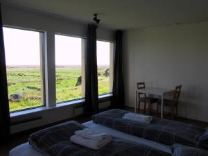 a bedroom with two beds and a table and windows at Rauðaberg II in Raudaberg