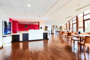 un restaurant avec des tables et des chaises en bois et des murs rouges dans l'établissement Kyriad Viry-Chatillon, à Viry-Châtillon