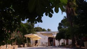 a house with tables and umbrellas in front of it at Le scuderie di Villa Ravenna Luxury House in Sannicola