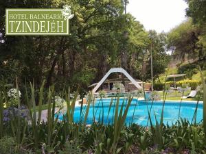 a swimming pool with a fountain in a garden at Hotel Balneario Tzindejeh in Tasquillo