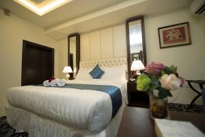 una habitación de hotel con una cama grande y un jarrón de flores en Rest Night Hotel Apartments Wadi Al Dawasir, en Wadi Al Dawasir