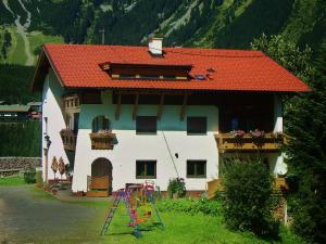 una casa con techo rojo y parque infantil en Haus Schöne Aussicht, en Berwang