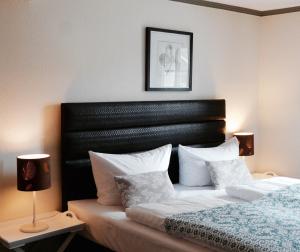 a bedroom with a bed with a black headboard and white pillows at Landfein Big Country House in Winterberg