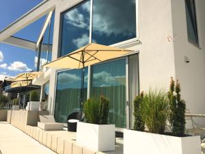 Weingut-Aparthotel Olinger في ميهرينغ: منزل به نوافذ زجاجية كبيرة ونباتات الفخار