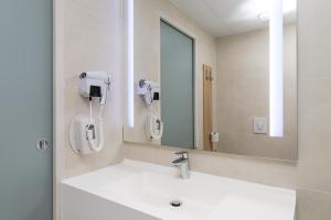 a bathroom with a white sink and a mirror at Campanile Metz Nord Woippy- Porte du Luxembourg A31- Confort Climatisé- Air Conditionning in Woippy +56 photos