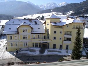 a large yellow building with snow on the roof at Hotel Kronplatz in Valdaora