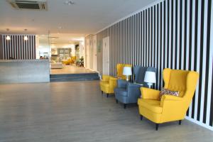 a waiting room with yellow chairs and a lobby at Vinha da Areia Beach Hotel in Vila Franca do Campo